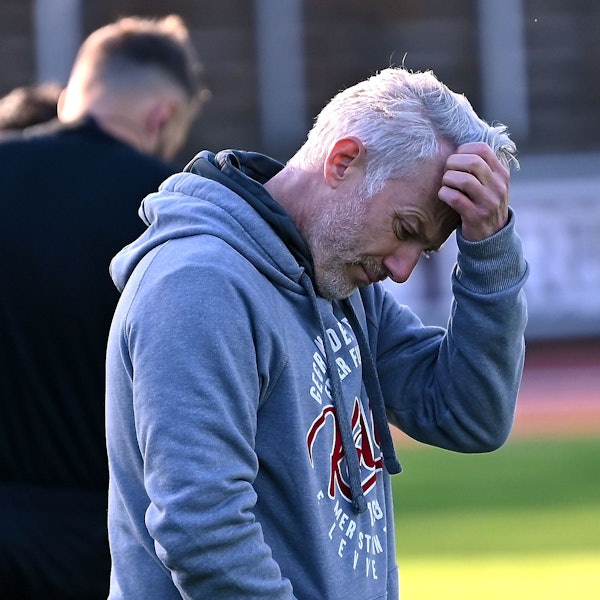 Ein Fußballtrainer kratzt sich nachdenklich am Kopf.