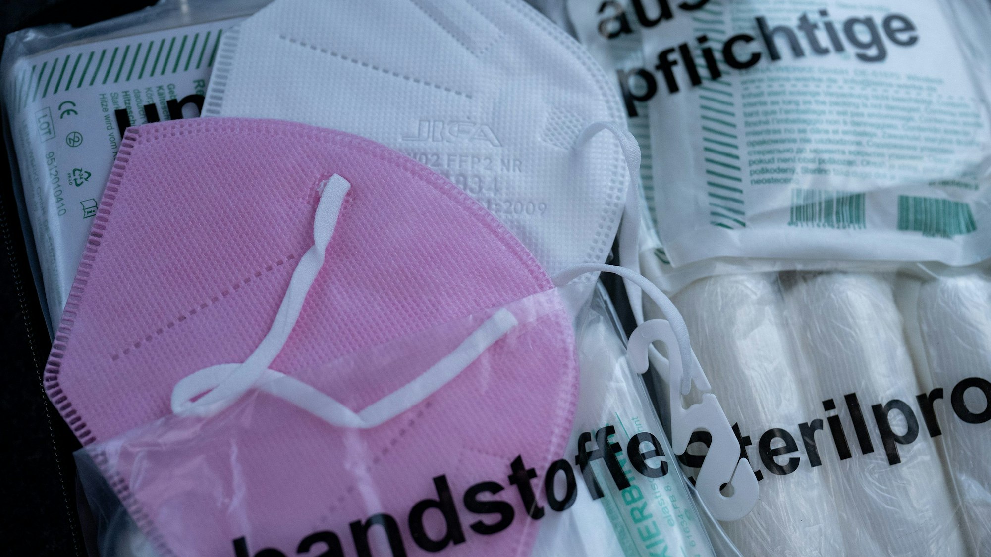 Zwei FFP2-Masken stecken in einer Verbandstasche in einem Auto.