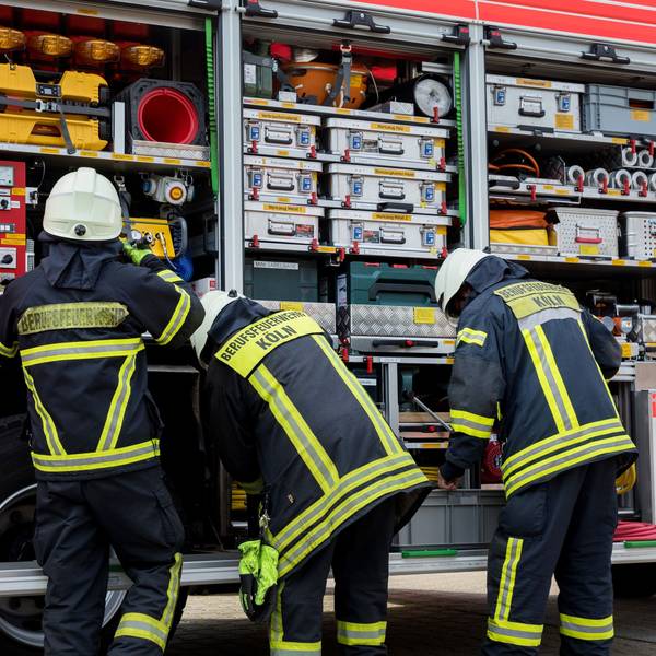 Feuerwehrleute stehen an einem Feuerwehrauto