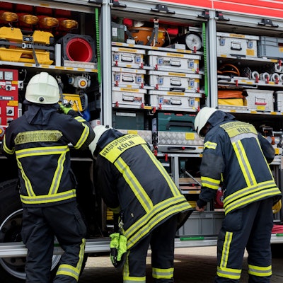 Feuerwehrleute stehen an einem Feuerwehrauto