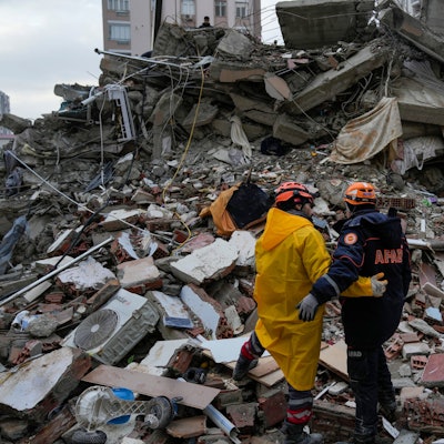 Türkei, Adana: Mitglieder eines Notfallteams halten einen Moment inne, während sie in einem zerstörten Gebäude nach Menschen suchen.