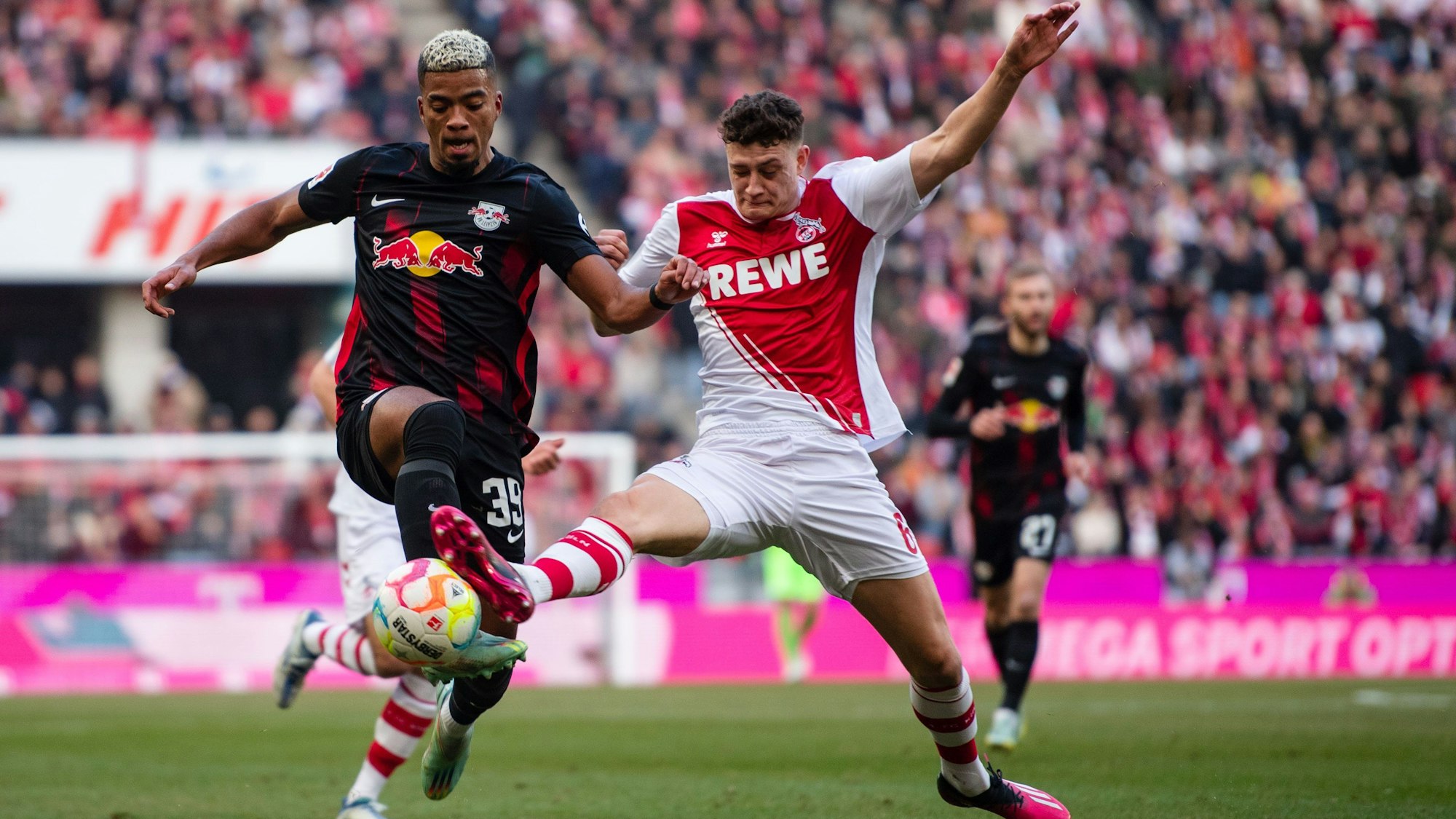 Leipzigs Benjamin Henrichs (l) und Kölns Eric Martel kämpfen um den Ball.
