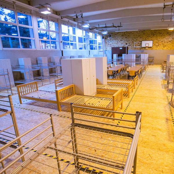 Eine Turnhalle ist mit Bettgestellen ausgestattet.