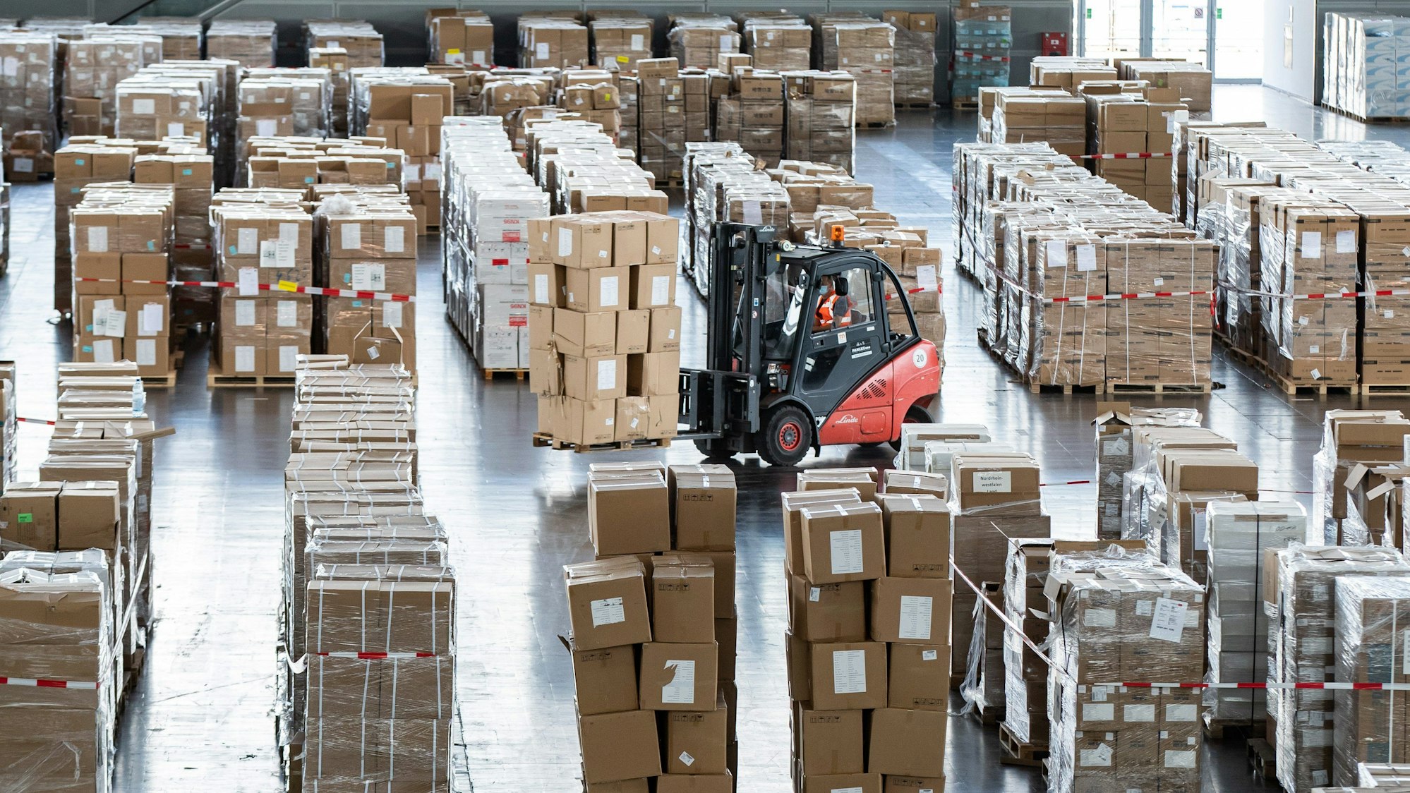 Ein Gabelstapler mit zahlreichen Kartons mit Schutzausrüstung fährt durch ein Lager.