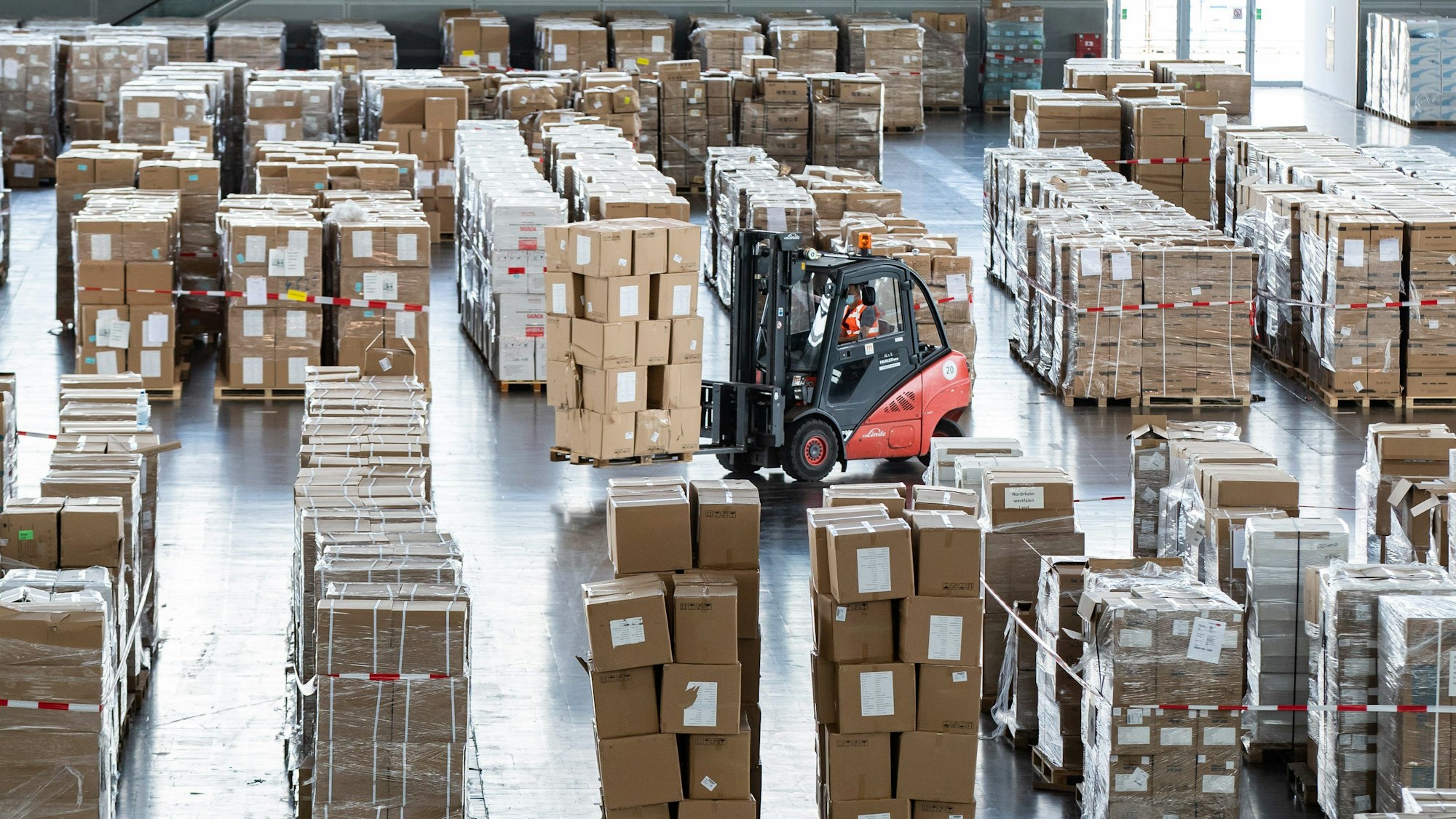 Ein Gabelstapler mit zahlreichen Kartons mit Schutzausrüstung fährt durch ein Lager.