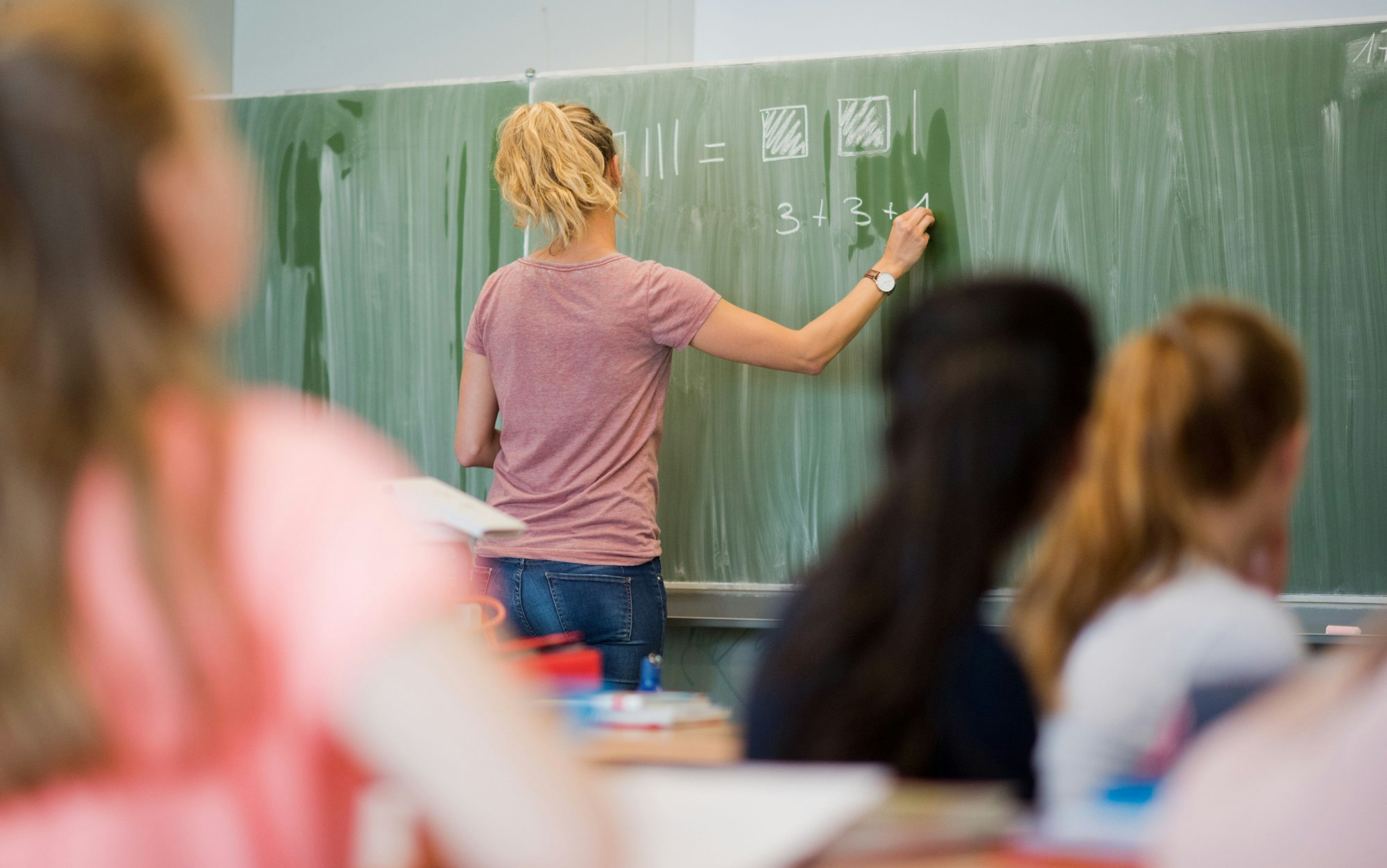 Eine junge Lehrerin schreibt an eine Schultafel im Mathematikunterricht an einer Integrierten Gesamtschule.