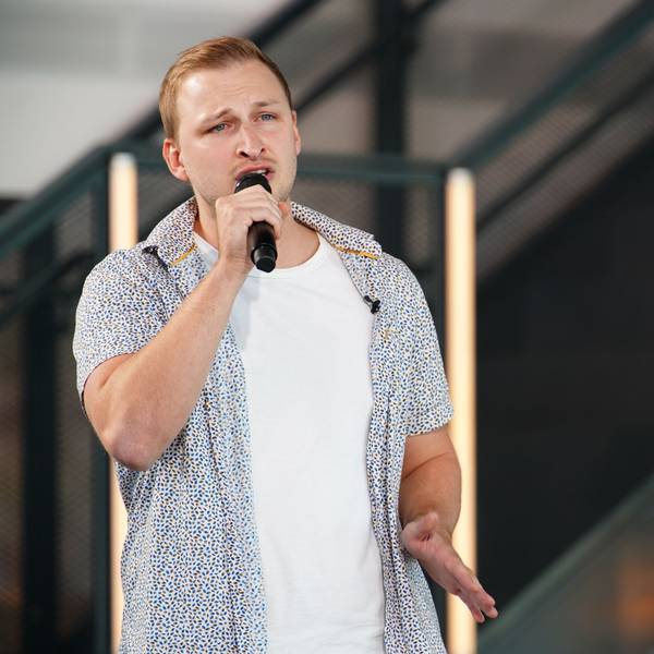 David steht auf einer Bühne und singt in ein Mikro.