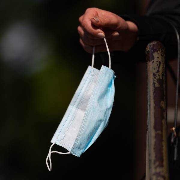 Ein Person hält ihren Mund-Nasen-Schutz in der Hand.