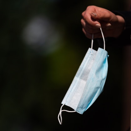 Ein Person hält ihren Mund-Nasen-Schutz in der Hand.