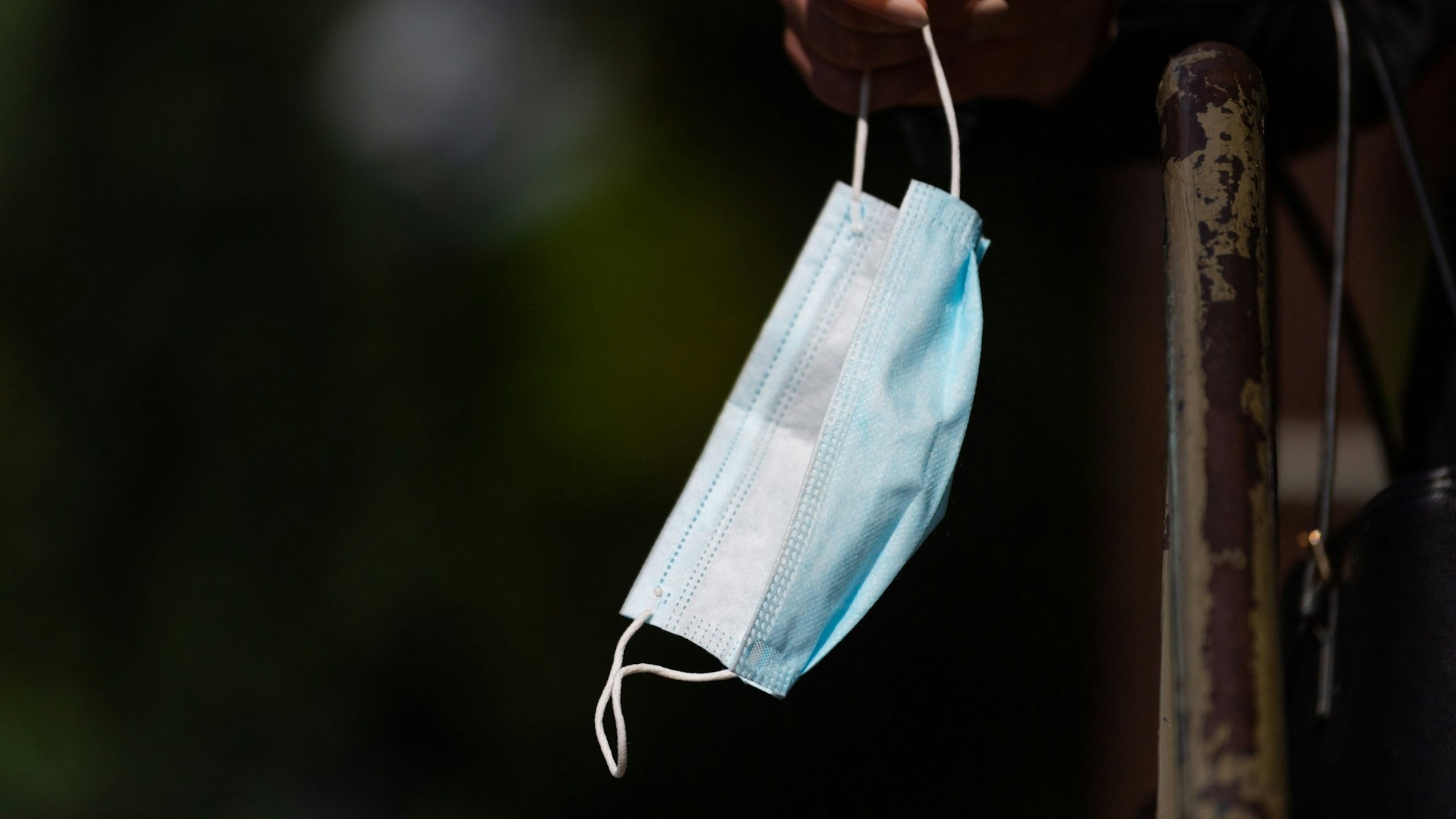 Ein Person hält ihren Mund-Nasen-Schutz in der Hand.