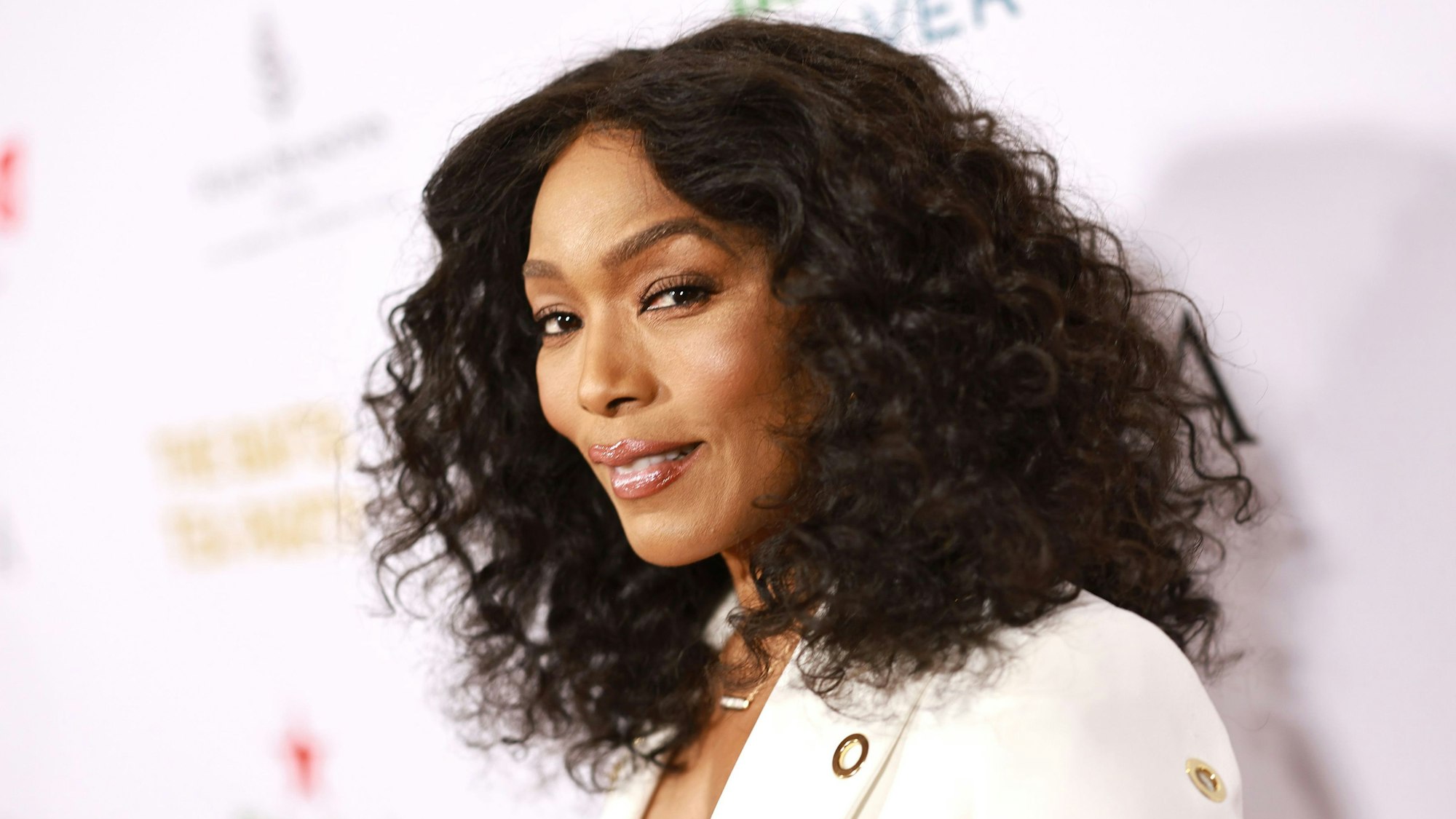 Angela Bassett mit lockigen Harren und weißem Outfit.