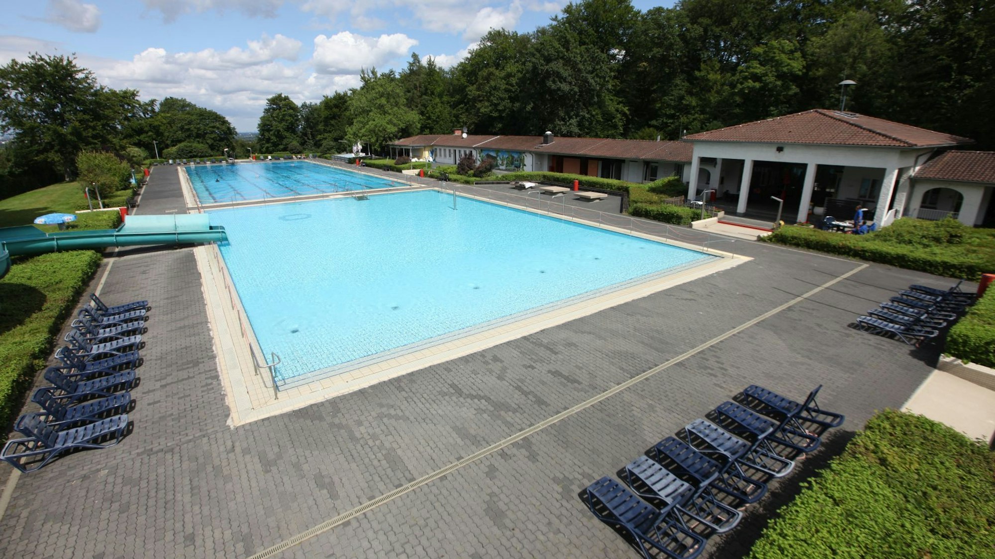 Blaue Liegen stehen am Rand der mit Wasser gefüllten Becken des Lemmerz-Freibades am Drachenfels in Königswinter.
