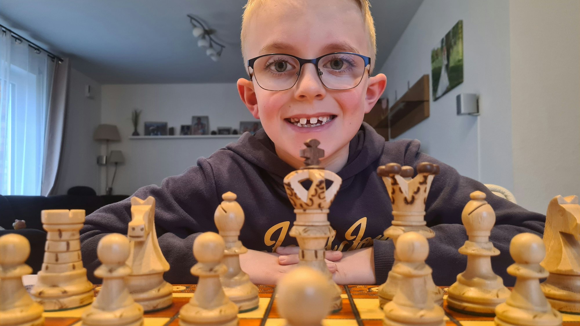 Nick sitzt hinter einem Schachbrett mit Figuren und schaut in die Kamera.