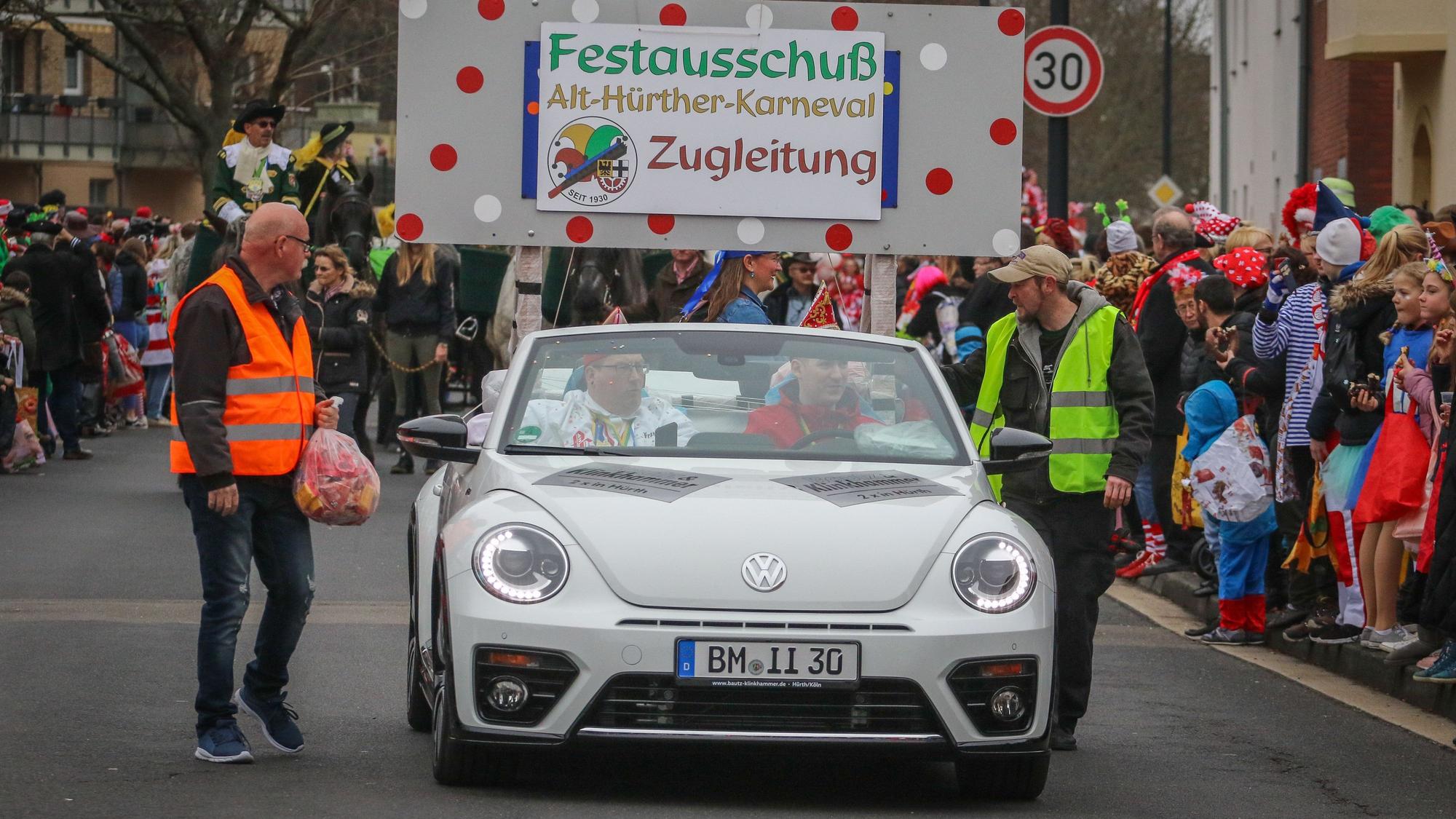 Auf dem Foto ist ein Karnevalszug zu sehen, der von Wagenengeln begleitet wird.