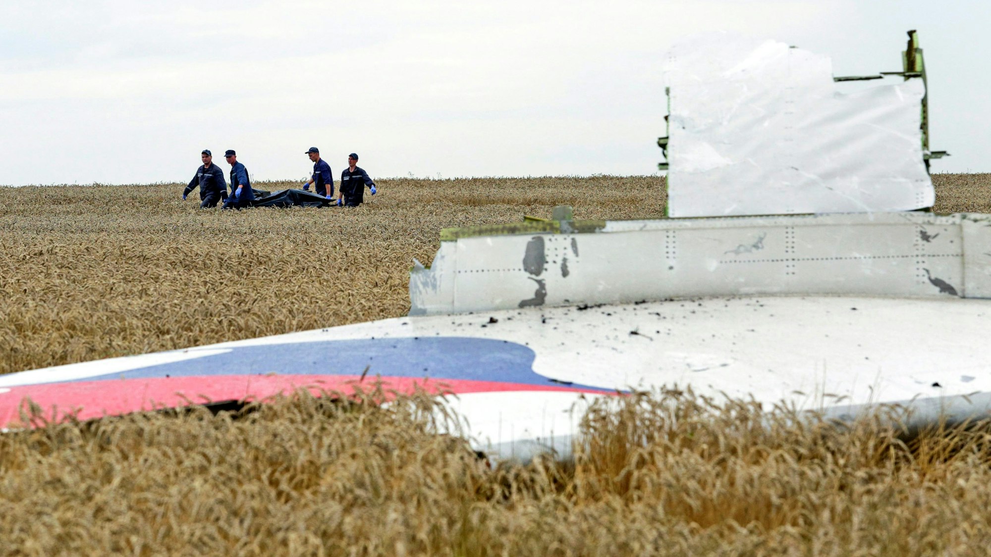 ARCHIV - 19.07.2014, Ukraine, Donezk: Einsatzkräfte transportieren eine Trage mit einem Leichensack durch ein Getreidefeld an der Absturzstelle der Boeing 777, die als Flug MH17 der Malaysia Airlines, beim Überfliegen der Ukraine, etwa 100 km östlich von Donezk, abstürzte. Der russische Präsident Putin spielte nach Erkenntnissen internationaler Ermittler eine aktive Rolle beim Abschuss des Passagierflugzeuges MH17 im Juli 2014 über der Ostukraine. Das geht aus abgehörten Telefongesprächen hervor, wie das Ermittlerteam am Mittwoch in Den Haag mitteilte. Foto: Anastasia Vlasova/EPA/dpa +++ dpa-Bildfunk +++
