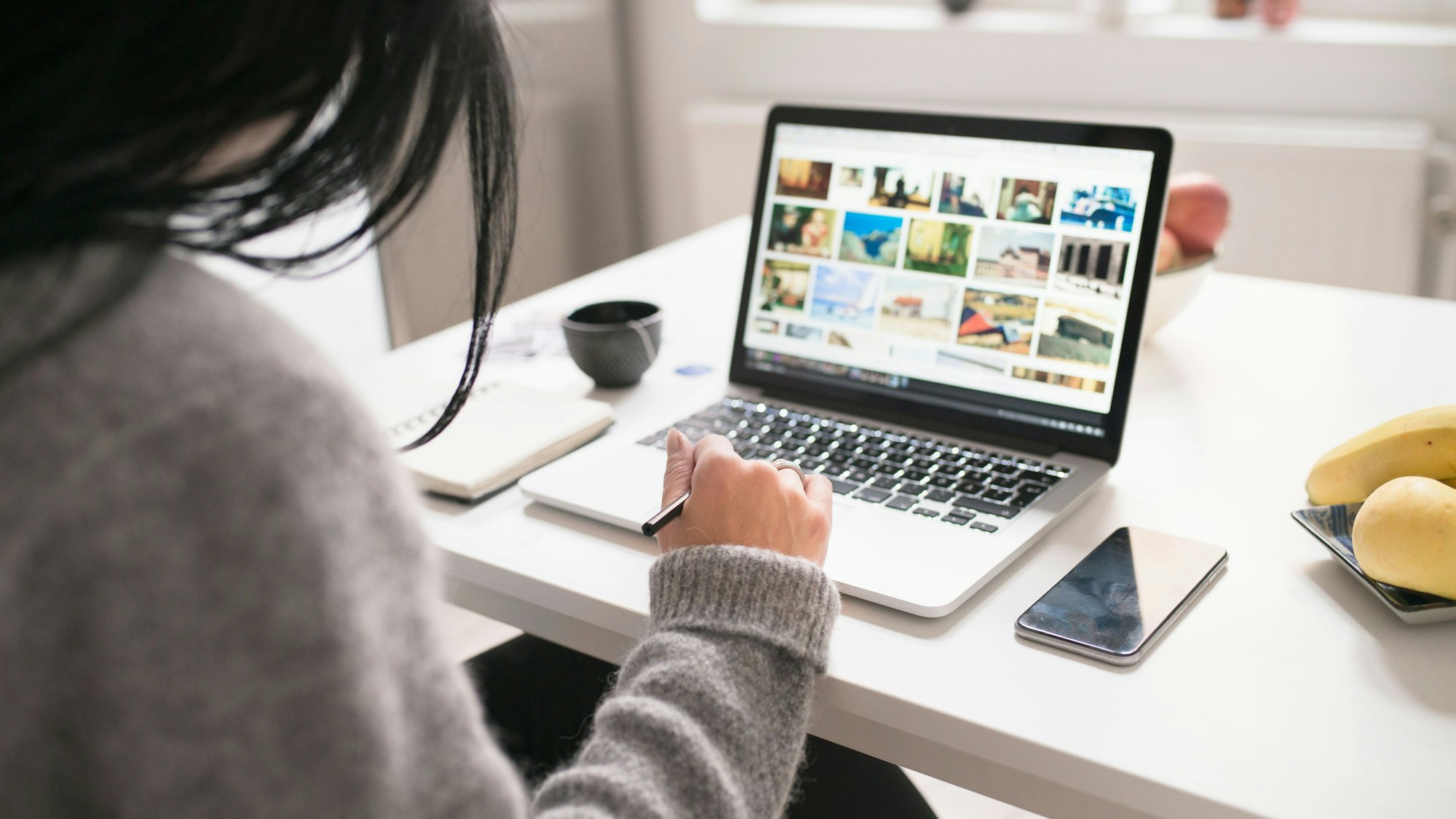 Es ist eine Frau zu sehen, die vor einem Laptop sitzt.
