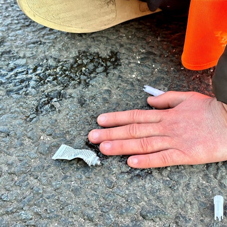 Eine Klimaaktivistin hat sich mit einer Hand auf einer Hauptverkehrsstraße festgeklebt.