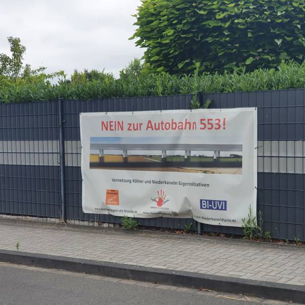 An einem Zaun in Niederkassel hängt ein Protest-Transparent gegen das Autobahn-Projekt Rheinspange 553.