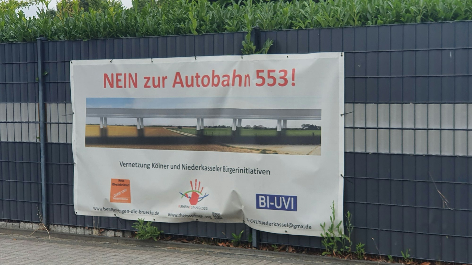 An einem Zaun in Niederkassel hängt ein Protest-Transparent gegen das Autobahn-Projekt Rheinspange 553.