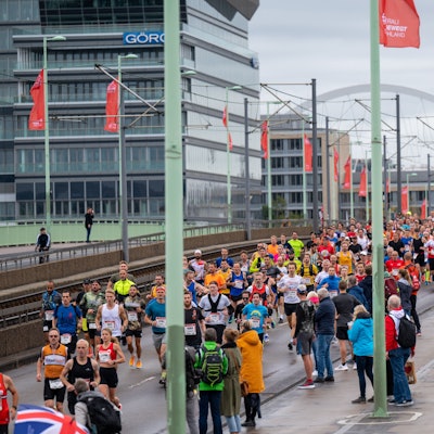Etliche bunt gekleidete Läuferinnen und Läufer überqueren die Deutzer Brücke.