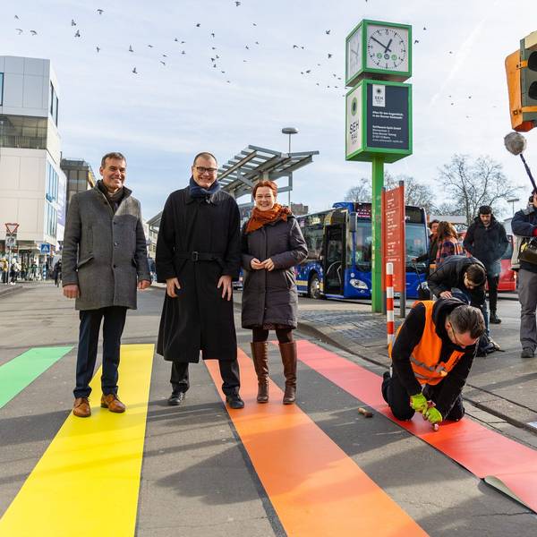 Zu sehen ist ein Straßenübergang in Bonn. Die Zebrastreifen sind regenbogenfarben.