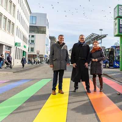 Zu sehen ist ein Straßenübergang in Bonn. Die Zebrastreifen sind regenbogenfarben.