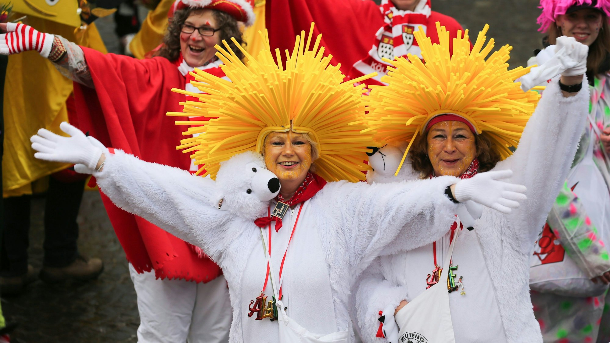 Es sind verkleidete Menschen zu sehen, die in die Kamera winken.