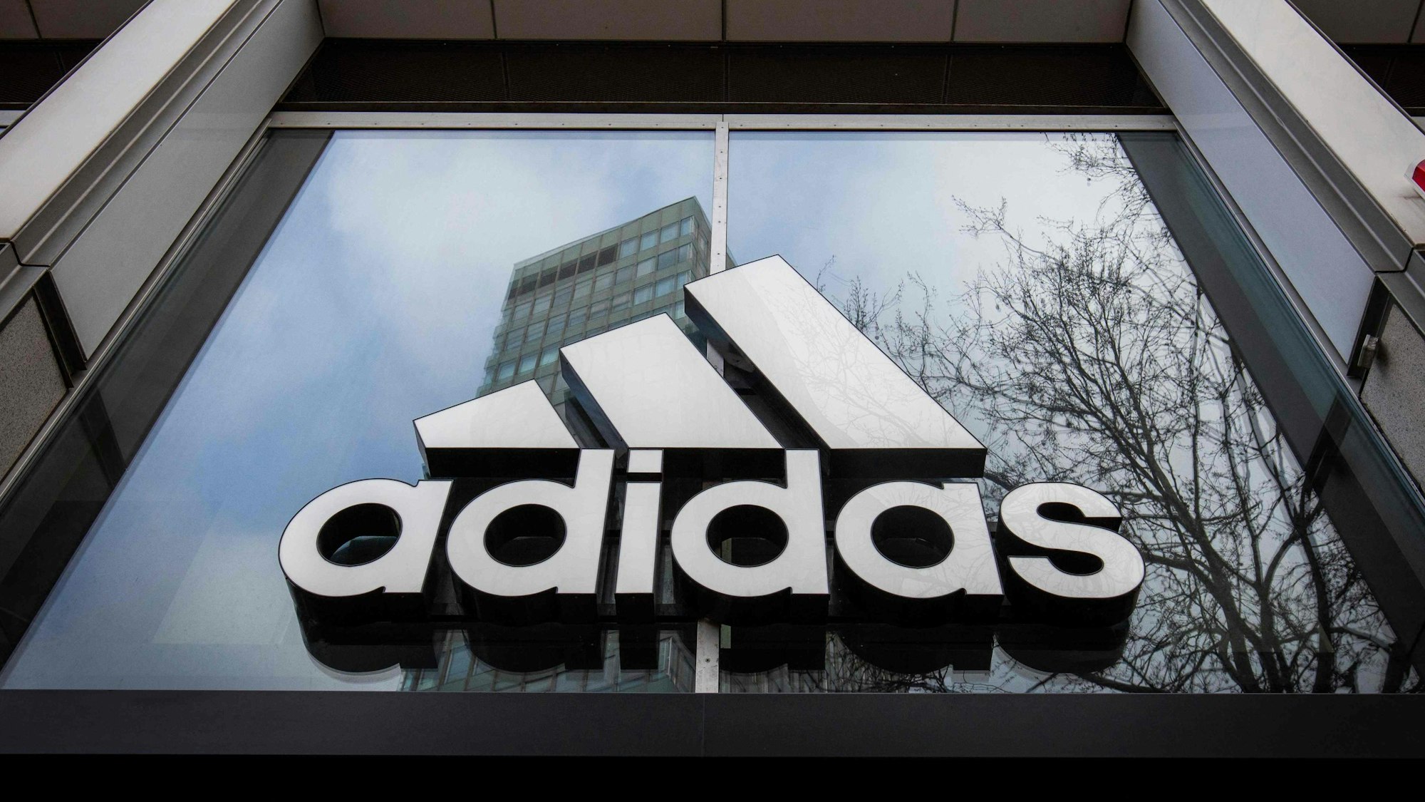 Das Adidas-Logo am Eingang eines Geschäfts.