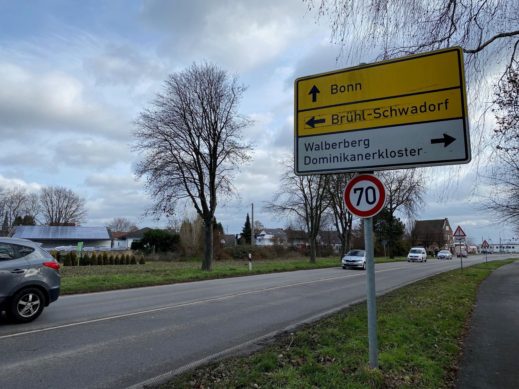 Es ist eine Straße mit einem Schild zu sehen, auf dem Brühl-Schwadorf als Richtung angegeben ist.