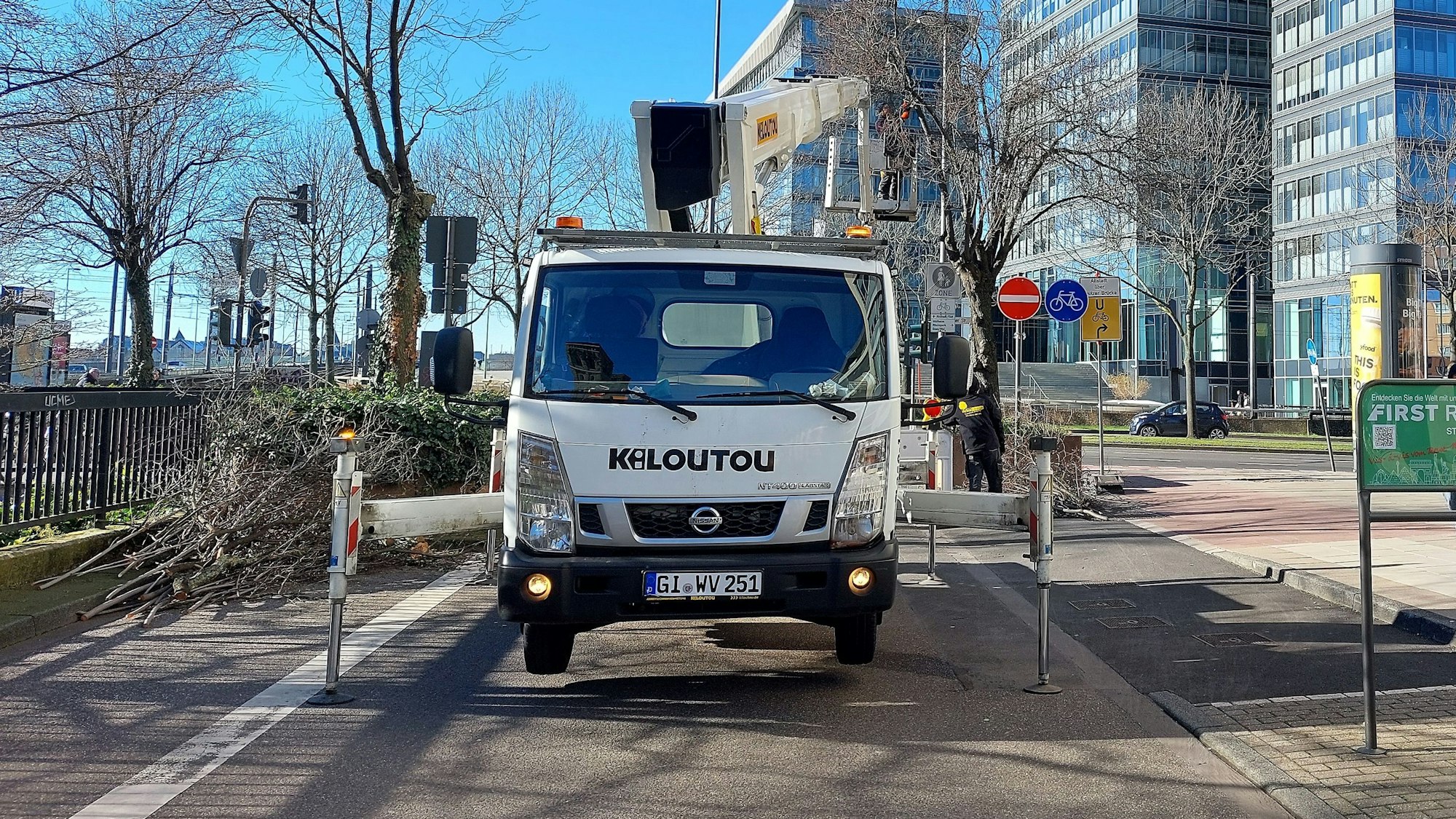 Ein Steigerwagen steht auf der Deutzer Freiheit. Ein Mann steht in dem Steigerkorb und sägt Äste von Bäumen.