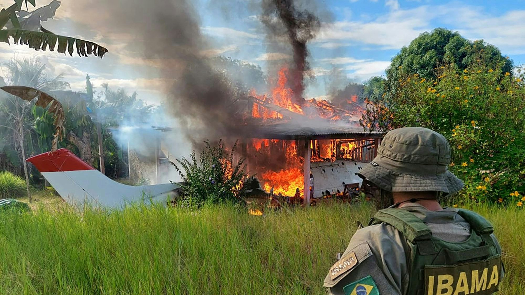Auf diesem von der brasilianischen Umweltbehörde IBAMA zur Verfügung gestellten Bild sieht ein Beamter zu, wie ein Gebäude und ein Flugzeug, die Bergleuten gehören, im Gebiet der Yanomami-Indigenen im brasilianischen Bundesstaat Roraima in Flammen aufgehen.