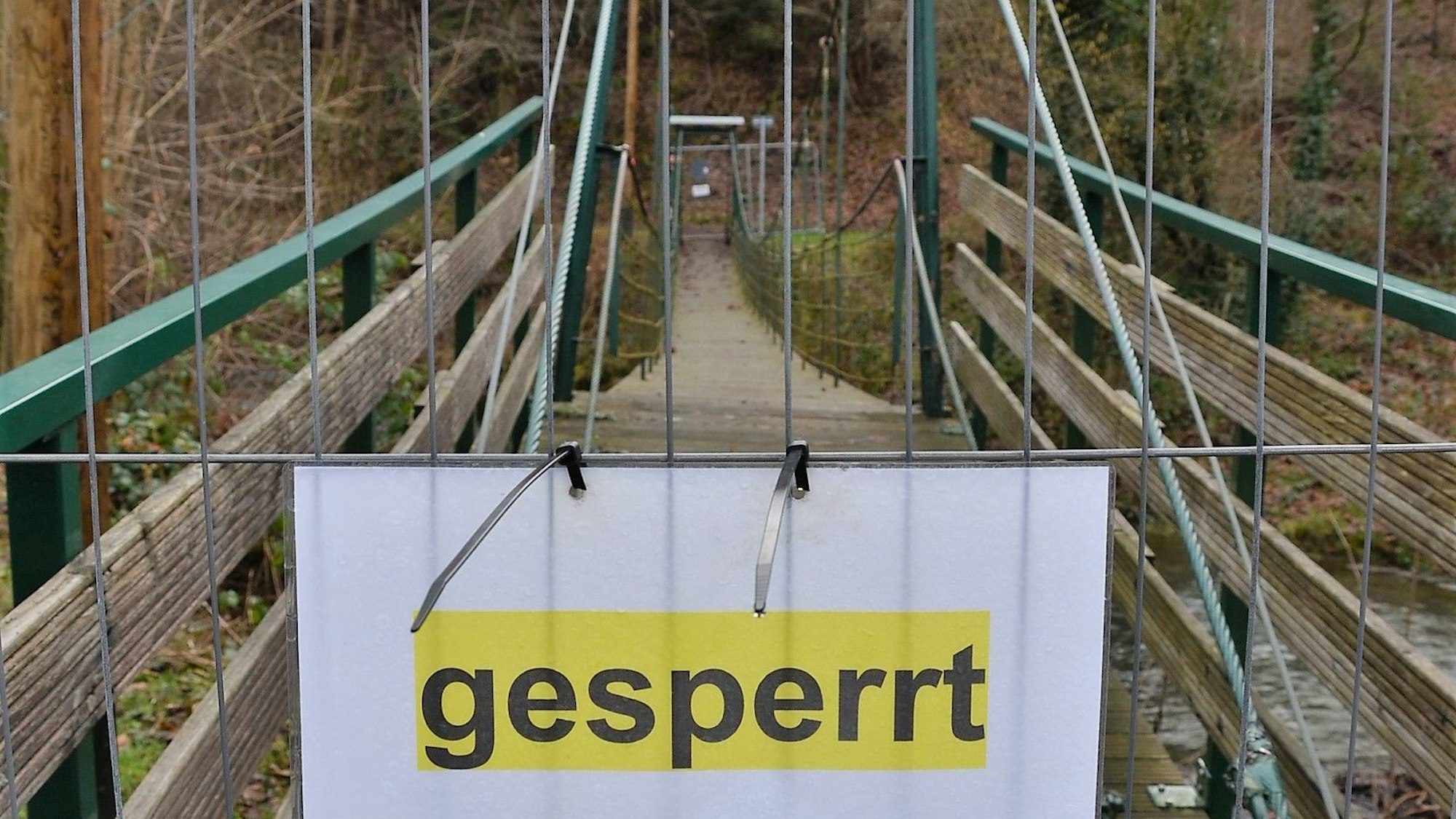 Es ist die abgesperrte Brücke mit einem Schild auf dem „gesperrt “ steht zu sehen.