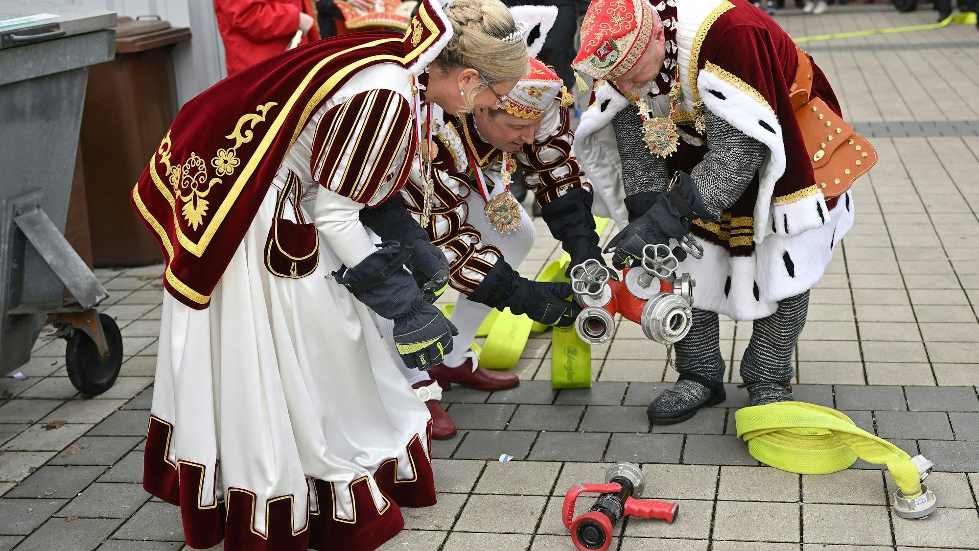Prinz, Bauer und Jungfrau verbinden Feuerwehrschläuche und Kupplungsstücke.