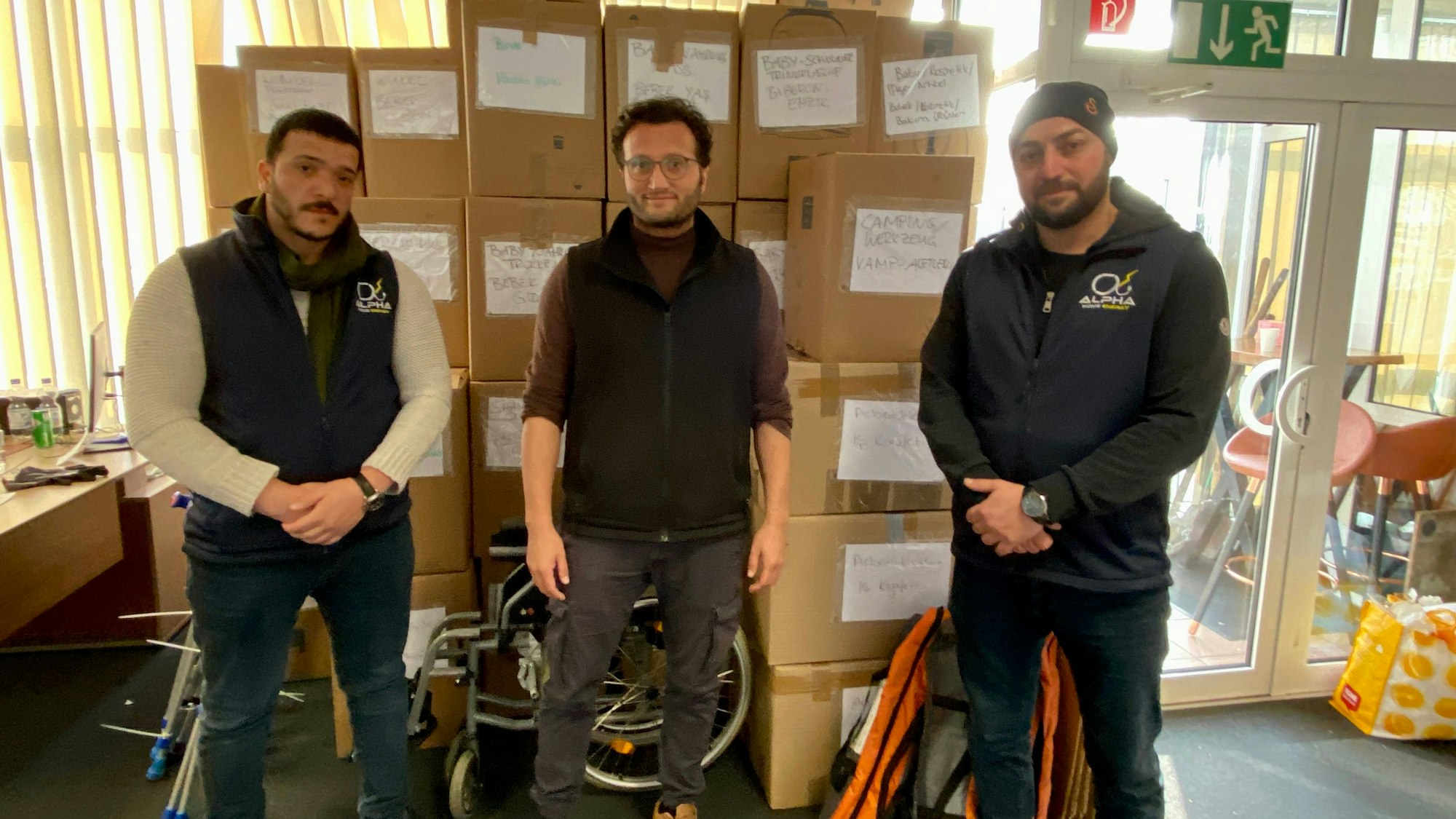 Pützer und seine zwei Helfer stehen vor gepackten Kisten mit Spenden.