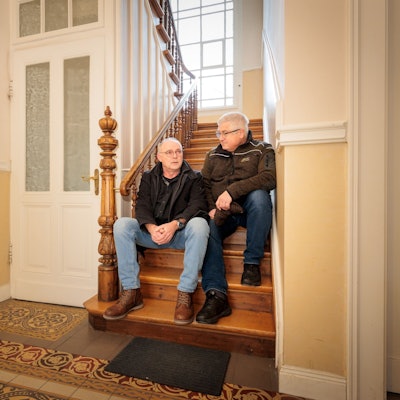 Zwei Männer sitzen auf einer alten Eichentreppe.