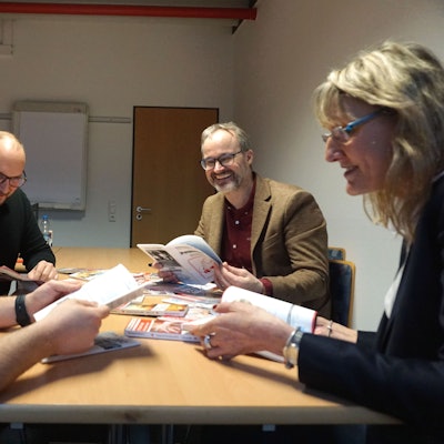 Die Leiter und Leiterinnen des DRK sitzen an einem Tisch und blättern durch Kataloge und Broschüren.