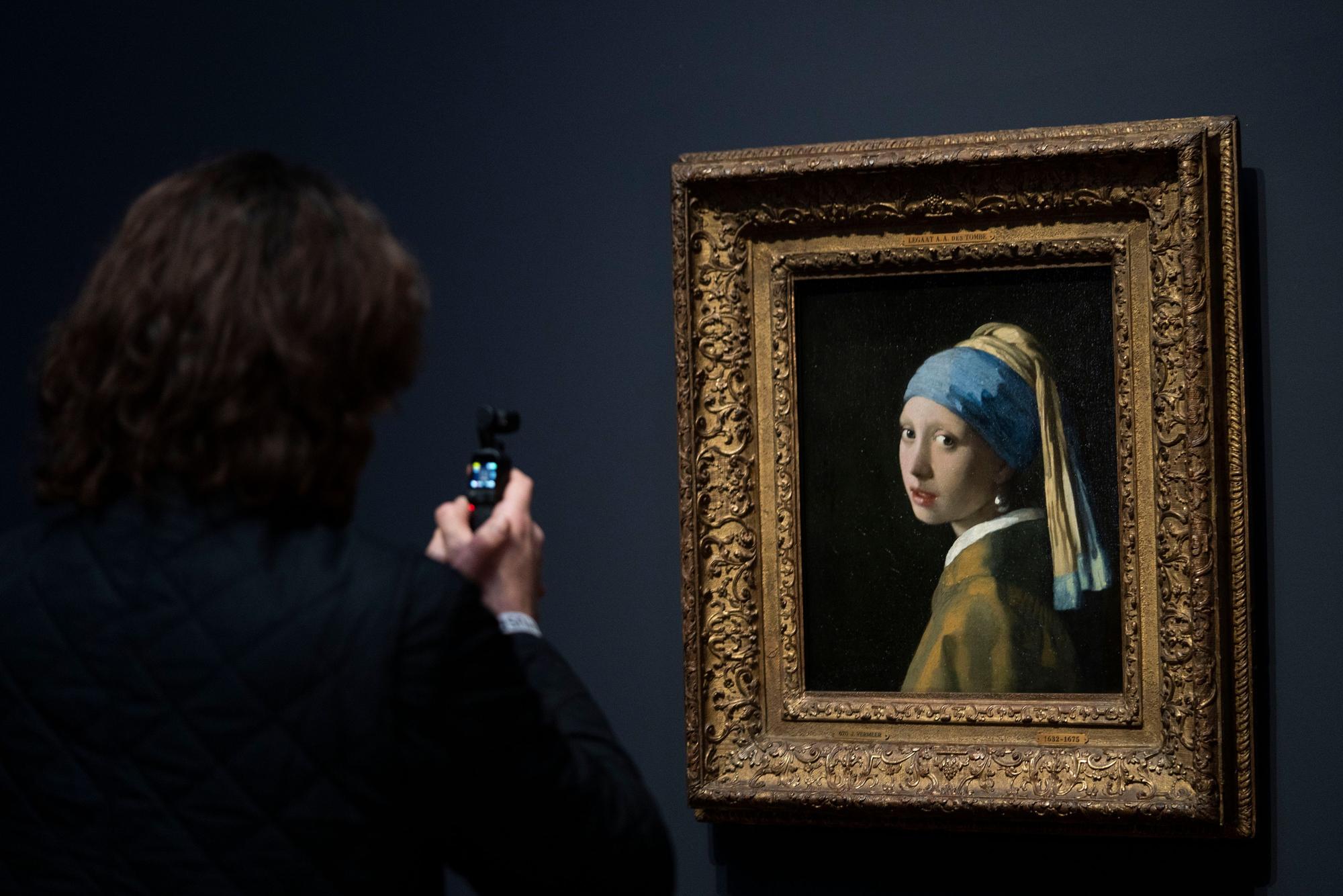 06.02.2023, Niederlande, Amsterdam: Eine Person fotografiert das Gemälde «Das Mädchen mit dem Perlenohrring» während eines Pressetermins für die Vermeer-Ausstellung im Amsterdamer Rijksmuseum.