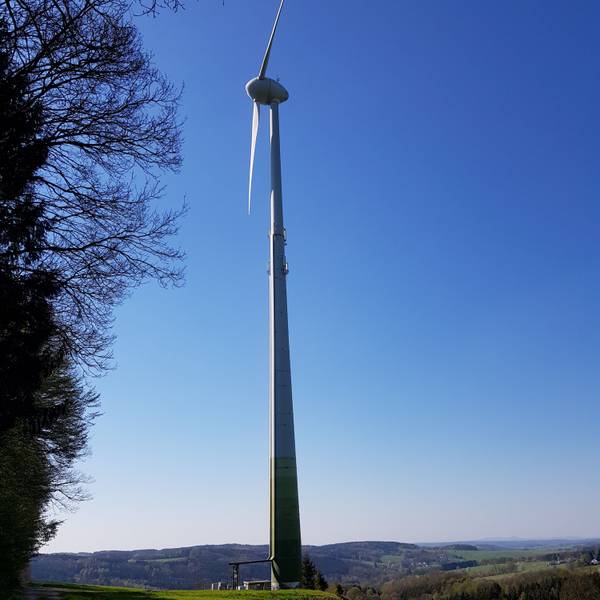 Die Flügel einer Windkraftanlage sind vor blauem Himmel zu sehen.