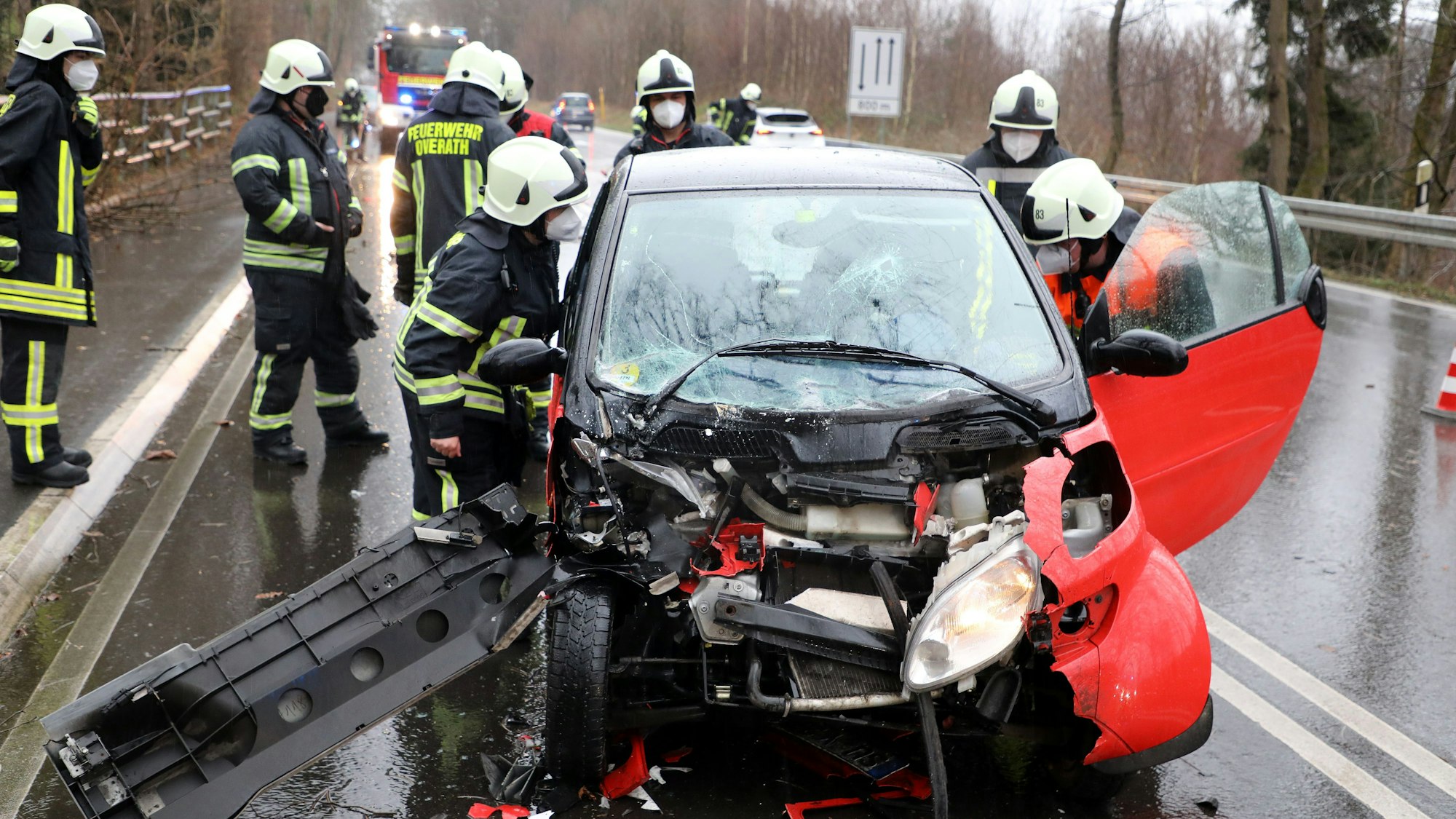 Einsatzkräfte der Feuerwehr stehen rund um einen demolierten PKW.
