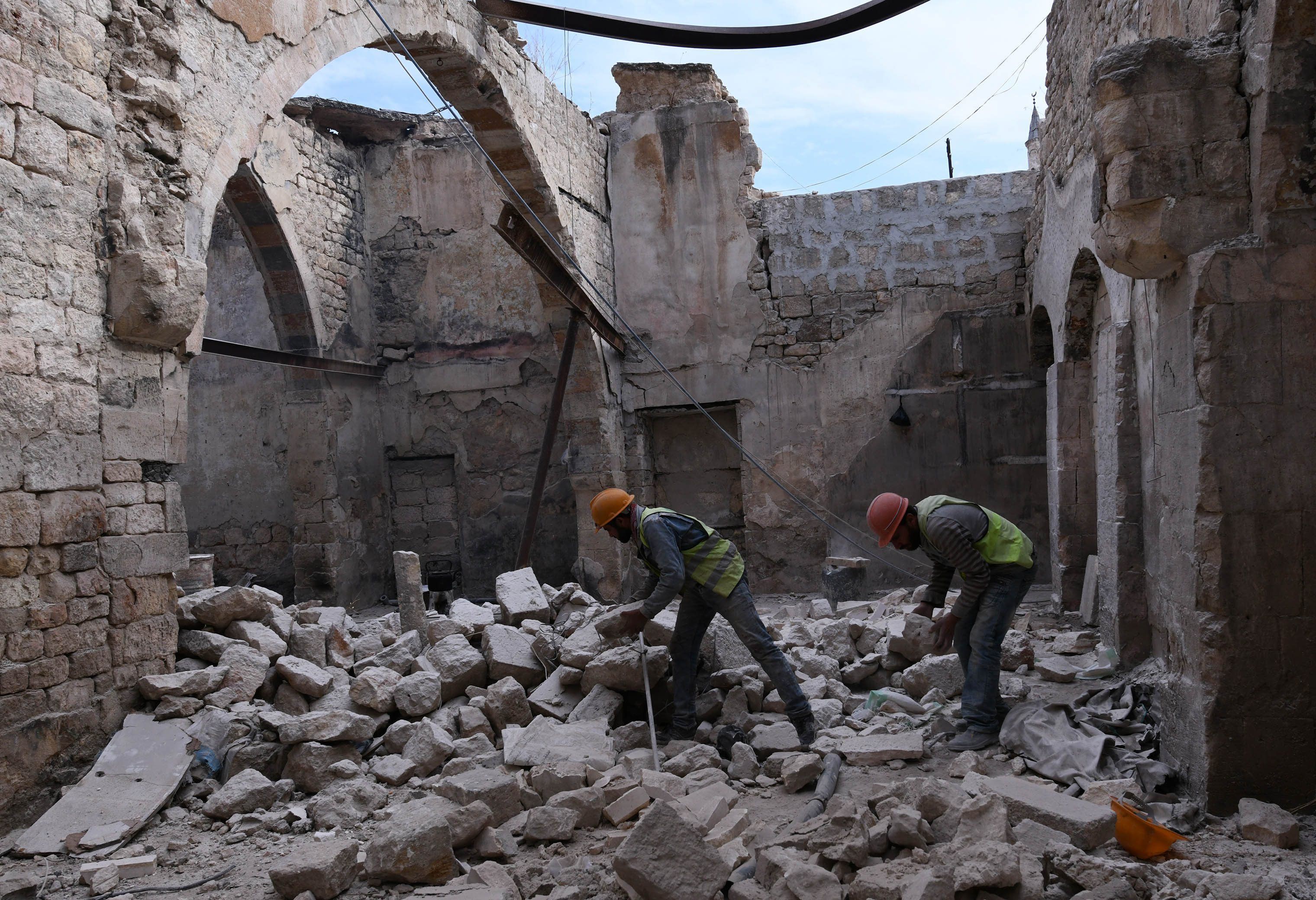 Bauarbeiter stehen beim Wiederaufbau des Khabiya Markts im historischen Viertel Souk der Altstadt von Aleppo zwischen Trümmern eines zerstörten Gebäudes. (2019)
