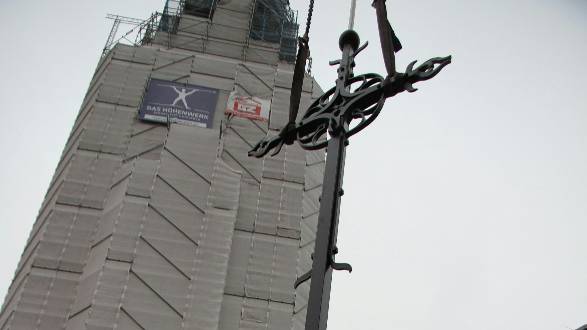 Der Turm der Kiche St. Anno in der Siegburger Nordstadt wird saniert, das Kreuz wurde jetzt wieder montiert.