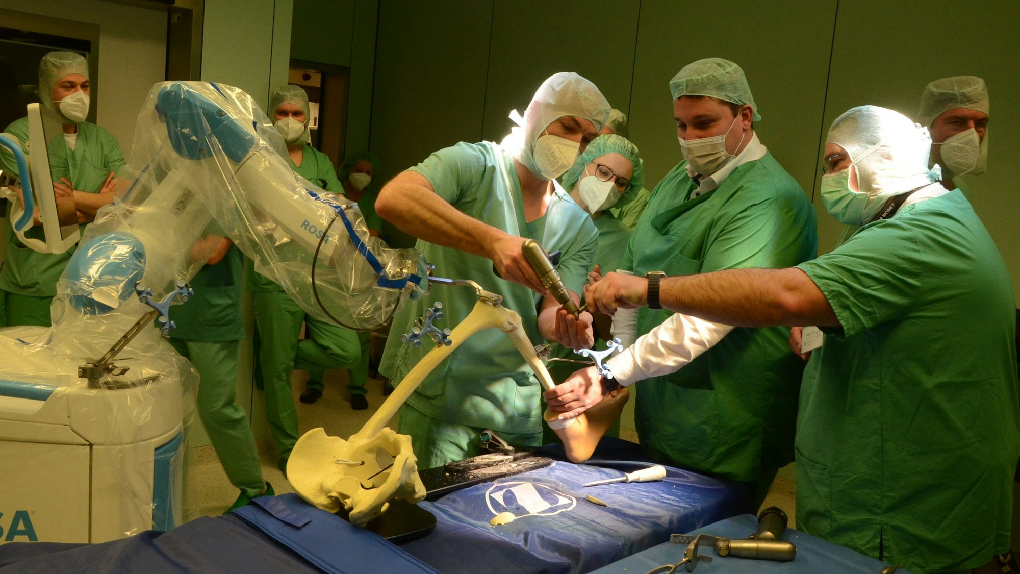 Ärzte behandeln gemeinsam mit einem Roboter ein künstliches Knie.