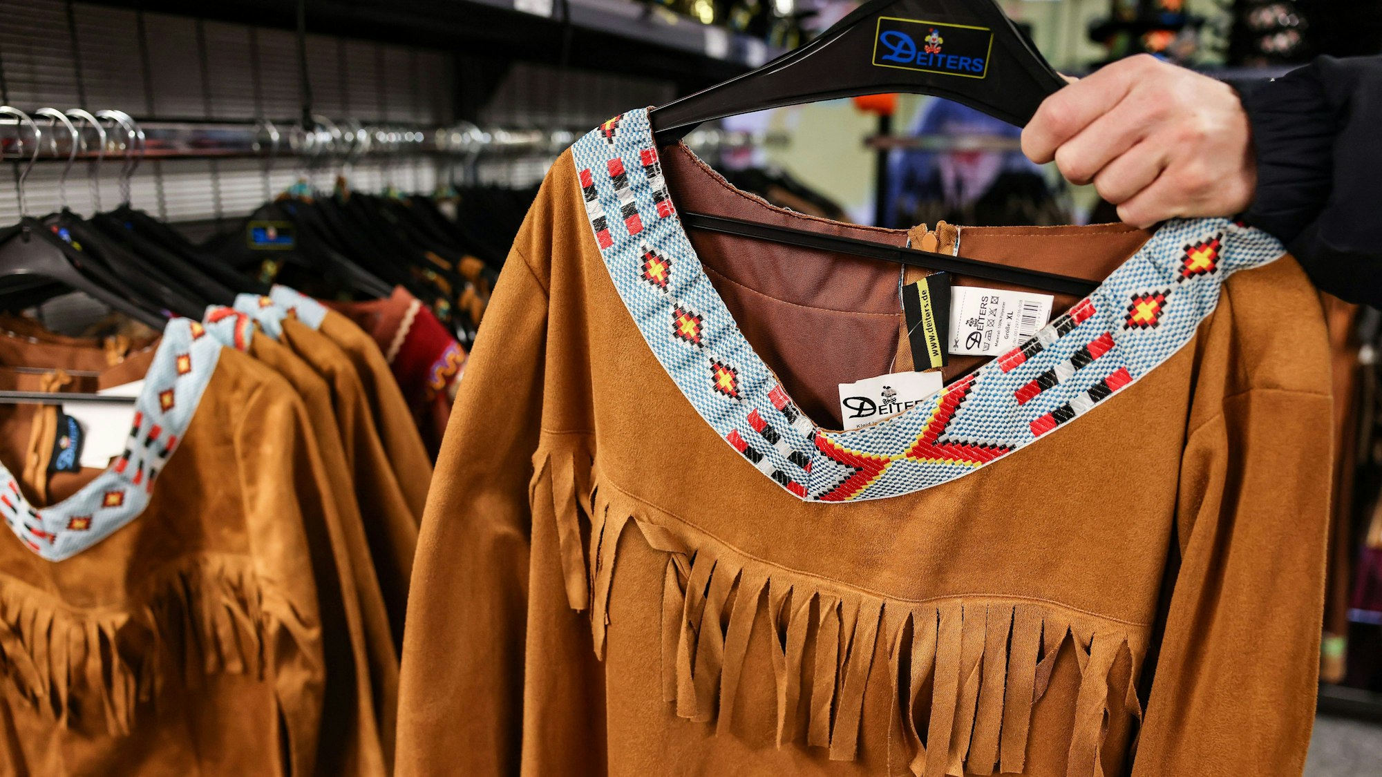 Ein Mann hält ein Kostüm zur Verkleidung als Indianer in der Hand.