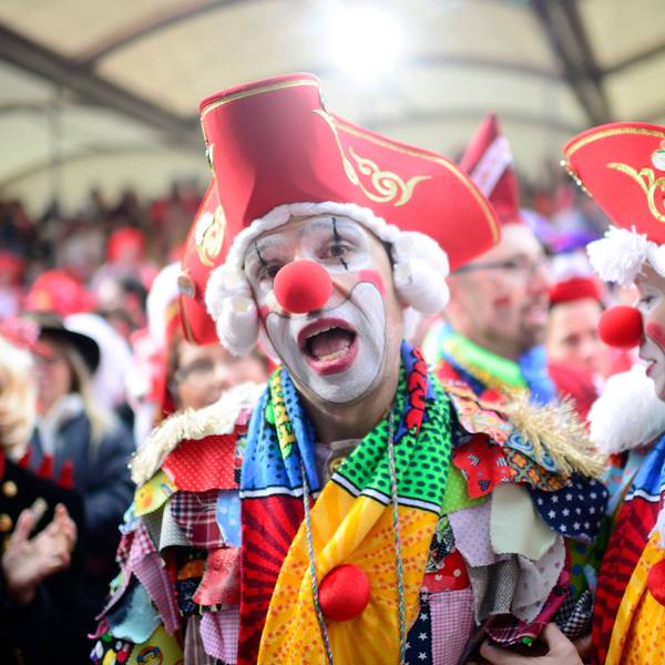 Ein als Clown verkleideter Mann mit roter Pappnase und rotem Hut steht vor der Tribüne am Alter Markt an Weiberfastnacht 2020.
