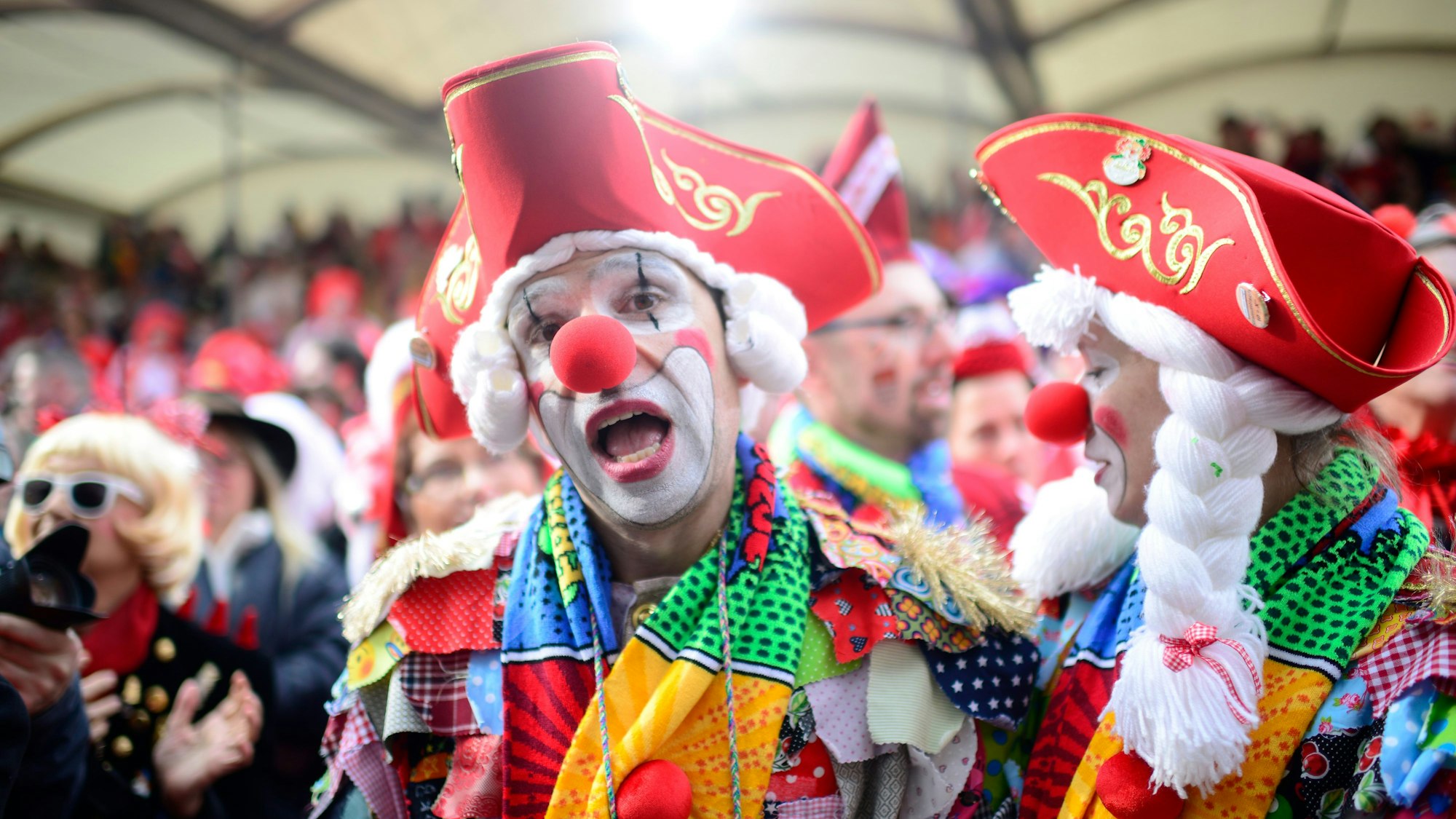 Ein als Clown verkleideter Mann mit roter Pappnase und rotem Hut steht vor der Tribüne am Alter Markt an Weiberfastnacht 2020.