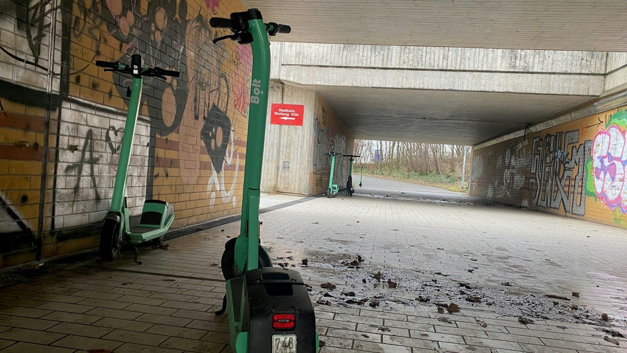 Mehrere E-Scooter stehen in einer Fußgängerunterführungen.