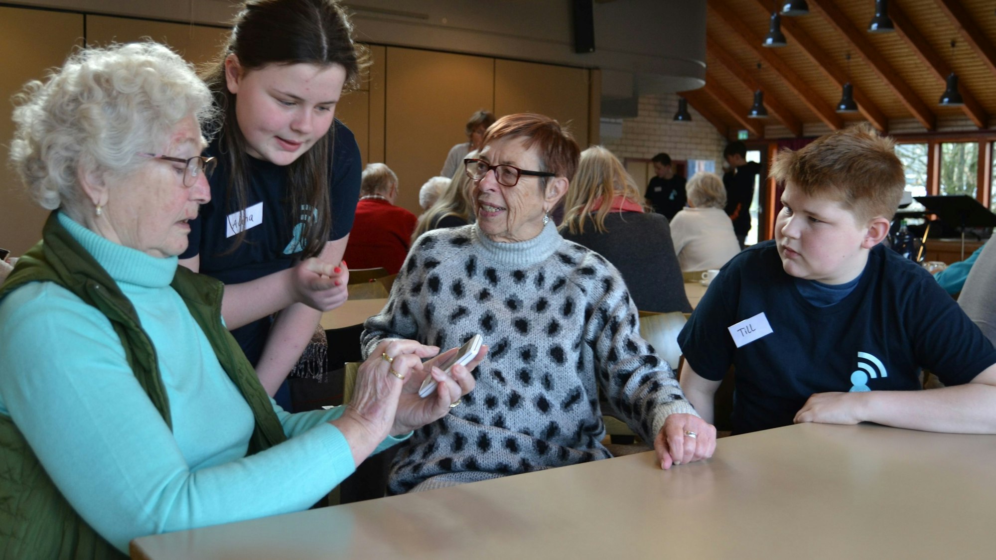 Von den Jugendlichen Alina und Till lassen sich Waldrud Schellenberg und Ursula Steppke das Smartphone erklären.