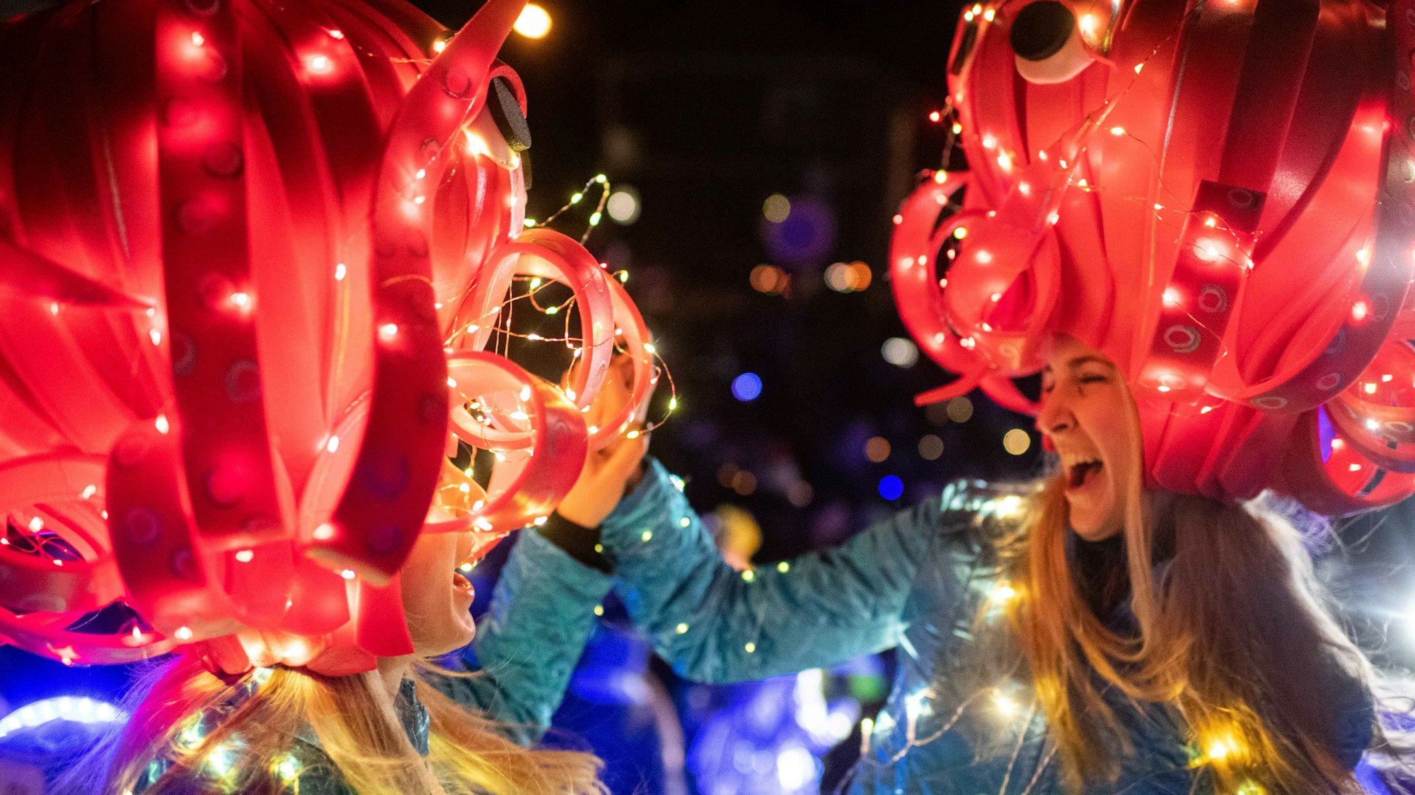 Zwei Karnevalistinnen tragen bunte und beleuchtete Kostüme.