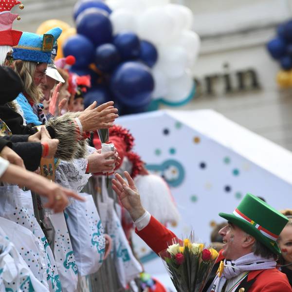 Karnevalisten auf dem Wagen verteilen Kamelle und Blumensträuße (Strüßjer) beim Rosenmontagszug.