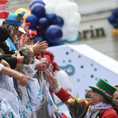 Karnevalisten auf dem Wagen verteilen Kamelle und Blumensträuße (Strüßjer) beim Rosenmontagszug.